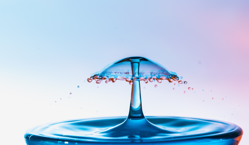 Зонтик из воды в стакане на сером фоне