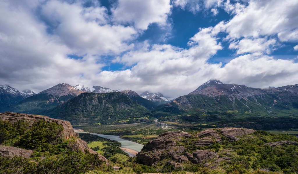 Белые облака в голубом небе над покрытыми зеленью горами
