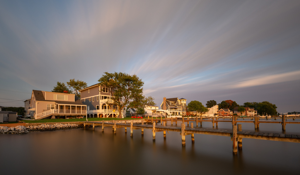 Мост у дома над тихой рекой под красивым небом