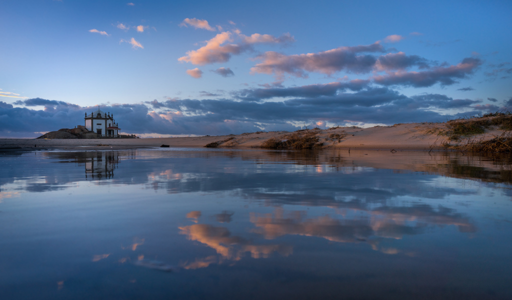Облака отражаются в спокойной воде озера 