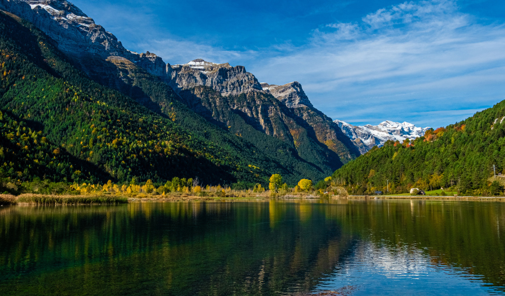 Холодная вода в чистом озере у горы под голубым небом