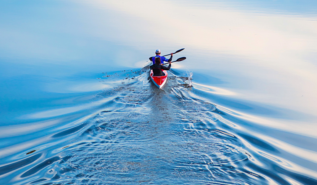 Два спортсмена на лодке плывут по реке 