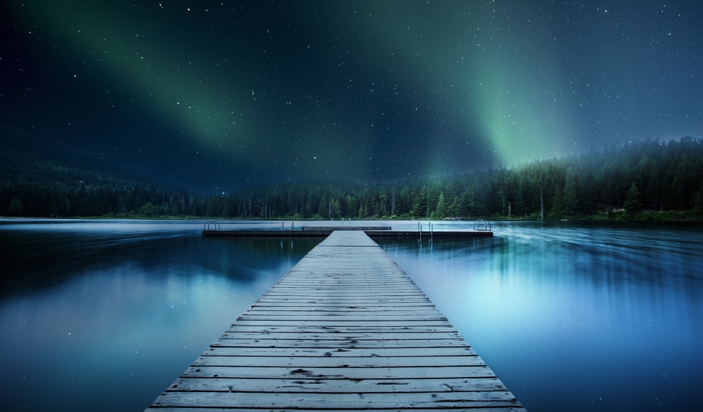 Wooden bridge on the lake under a beautiful night sky