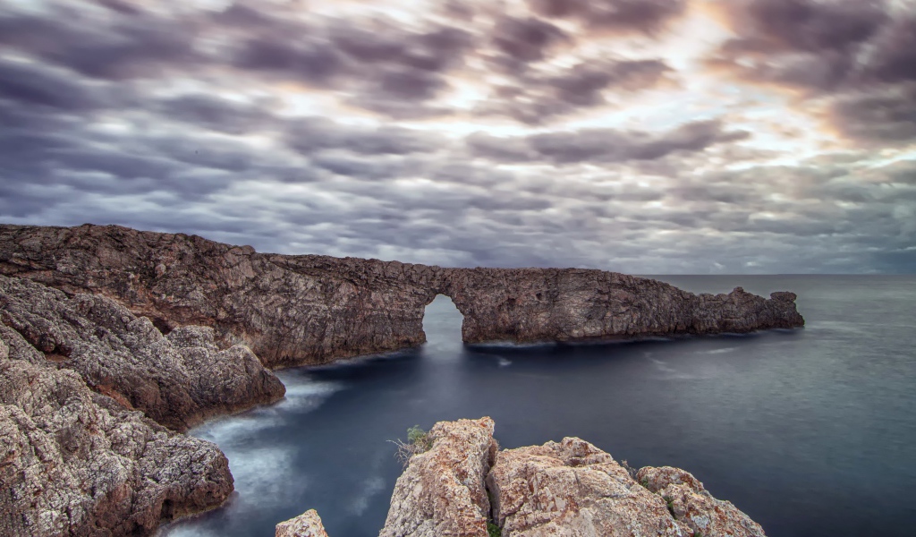 Арка в скале в море под пасмурным небом 