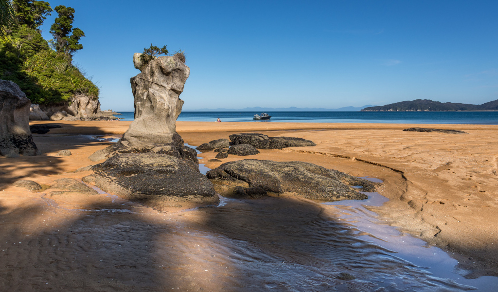 Большие камни на берегу на мокром песке у моря летом 