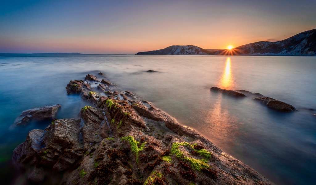Спокойная вода в море с подводными камнями на закате 