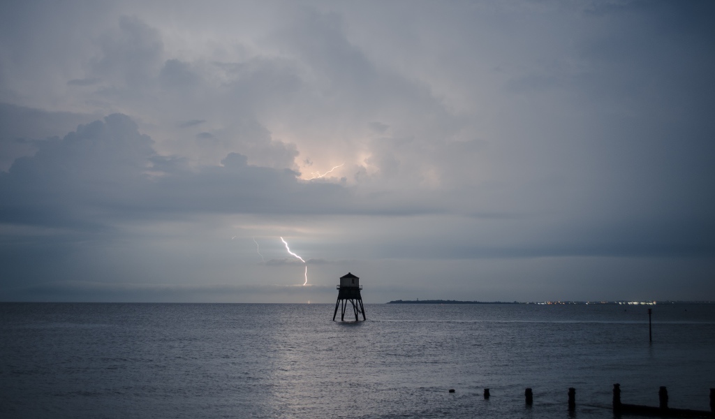 Старая башня в море на фоне грозы 