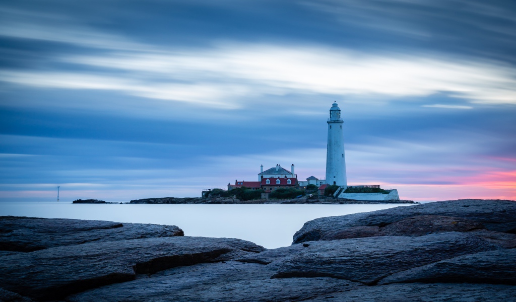 Вид с каменного берега на маяк в море 