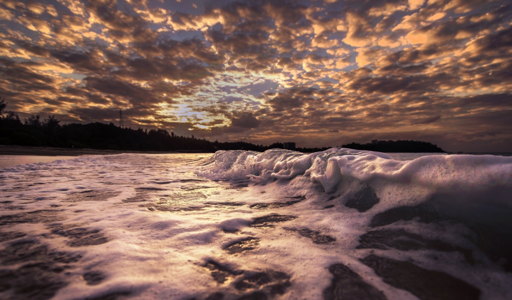 Белые волны на песке на рассвете 