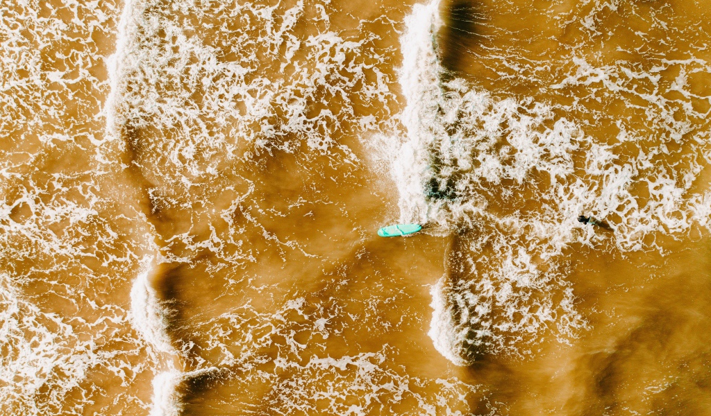 Белые волны на воде поднимают песок