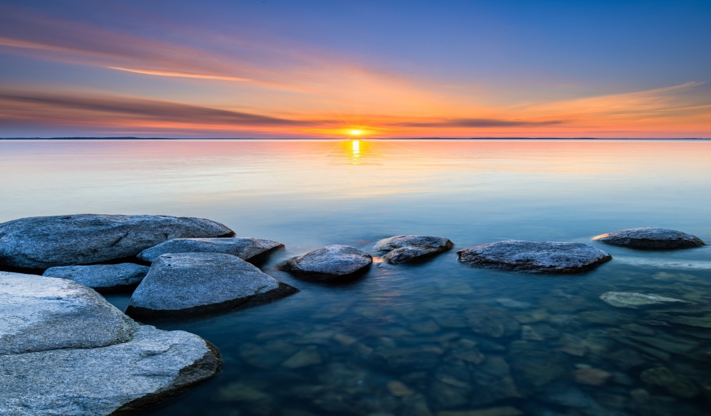 Большие камни в воде на закате яркого летнего солнца 