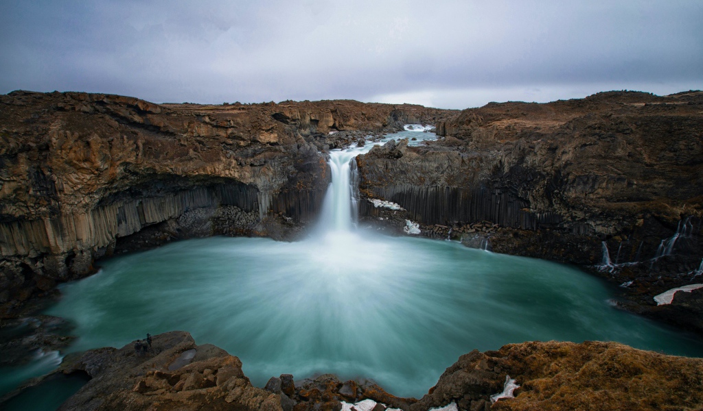 Красивый водопад стекает с каменной скалы в озеро 