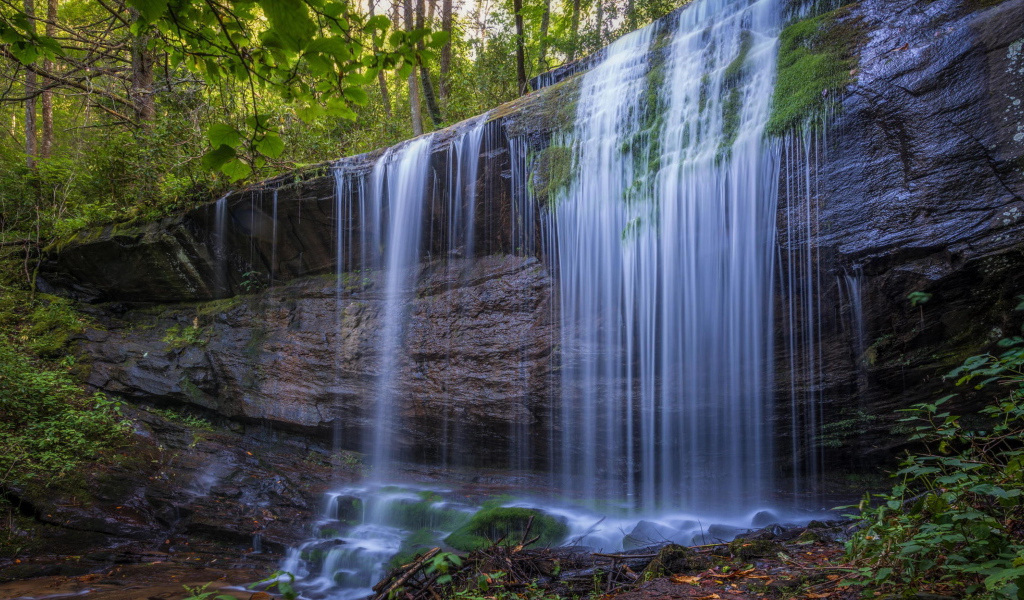 Холодная вода водопада стекает по мокрой скале