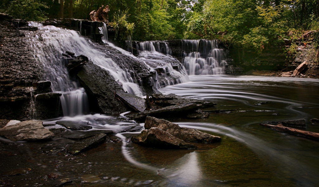 Быстрая вода стекает по камням водопада в парке 