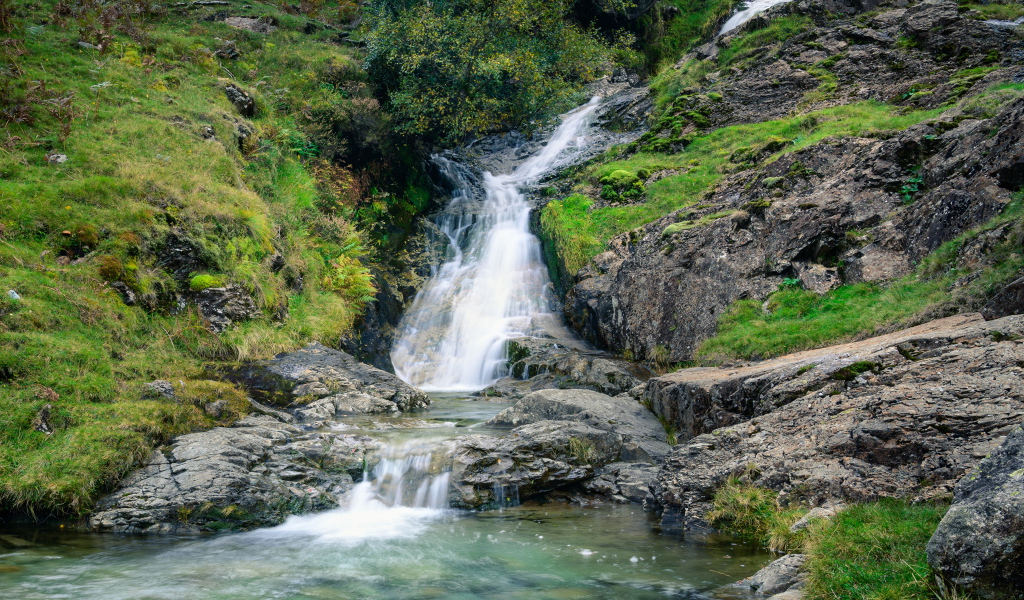 Горный ручей стекает по камням в реку 