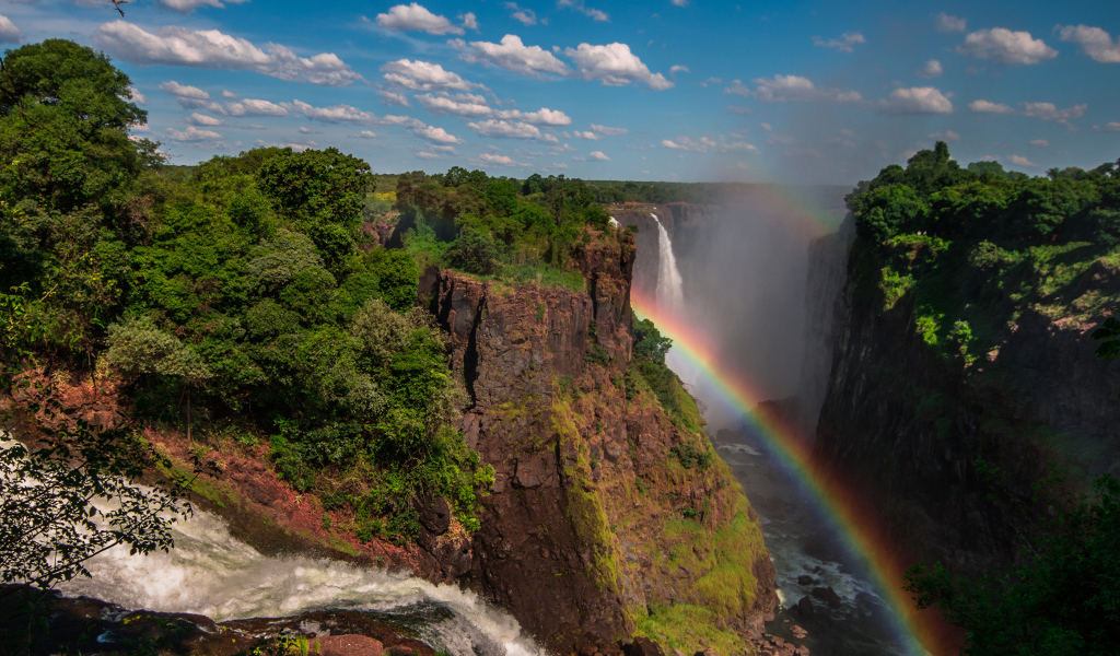 Радуга над водопадом на утесе 