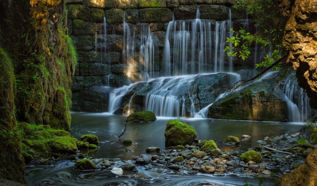 Водопад пробивается сквозь покрытые мхом камни 