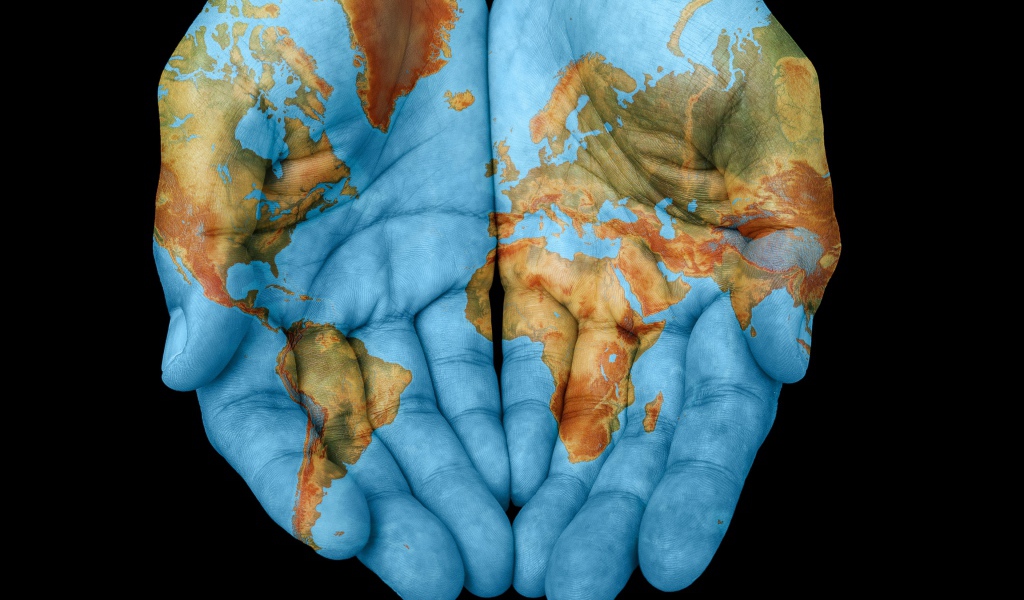 Руки с картой мира на черном фоне 
