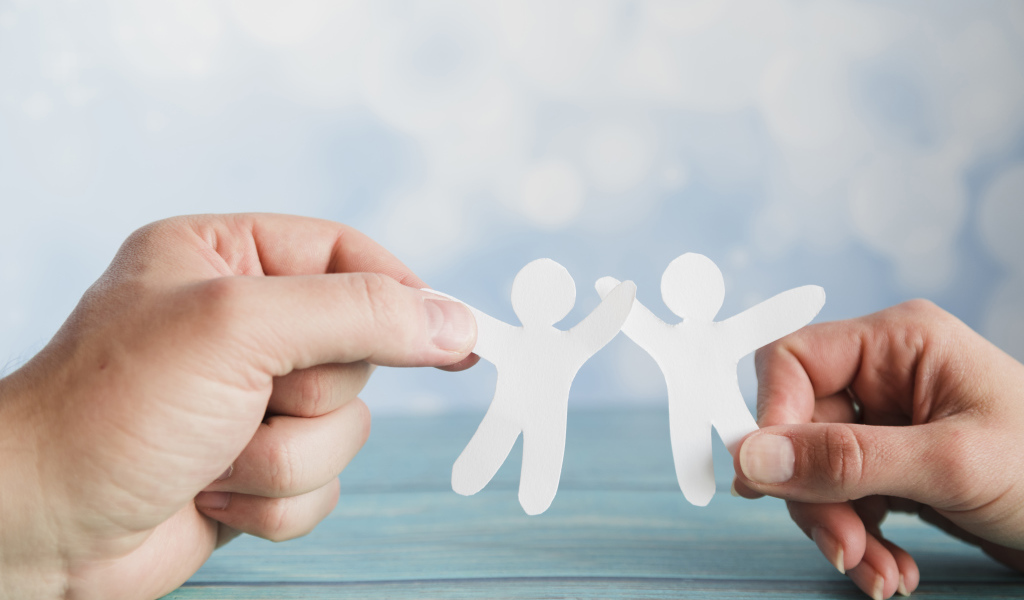 Два бумажных человечка в руках 