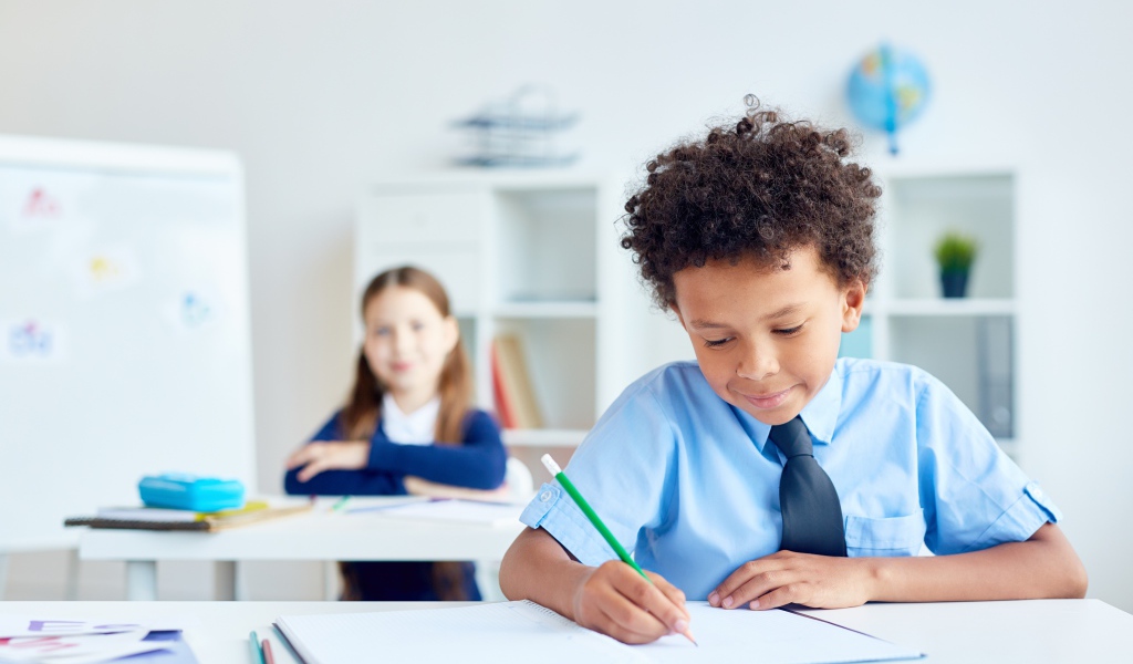 Маленький мальчик сидит за партой в классе