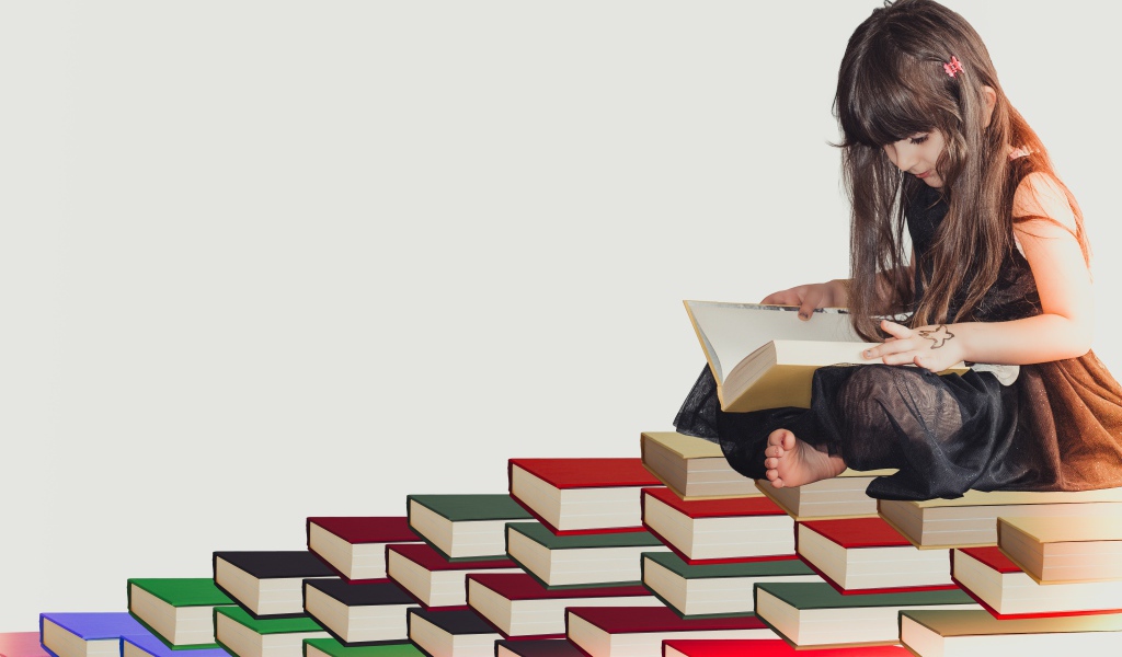Маленькая девочка сидит на горе книг 