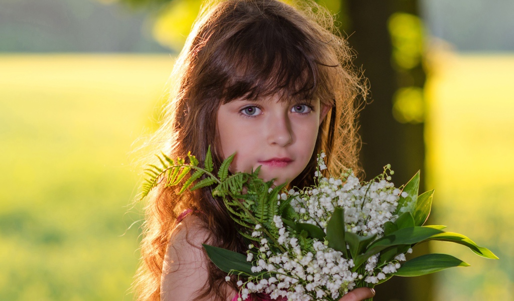 Красивая маленькая девочка с букетом ландышей в руке