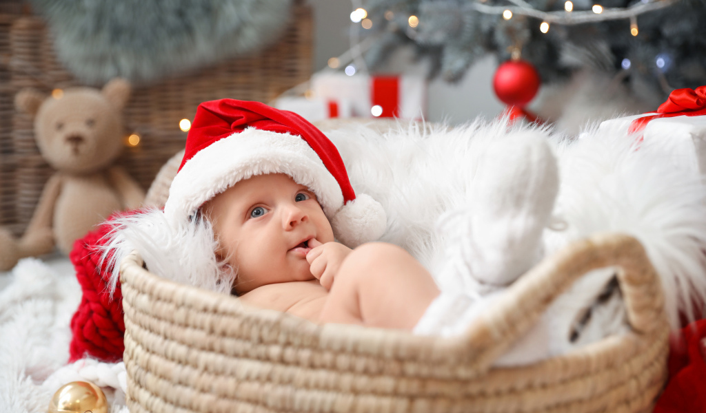 Милый малыш в шапке Санта Клауса лежит в корзине