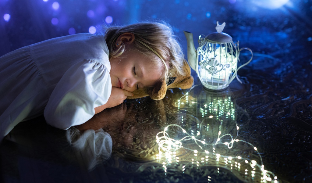 Милая маленькая девочка в белом платье спит на столе