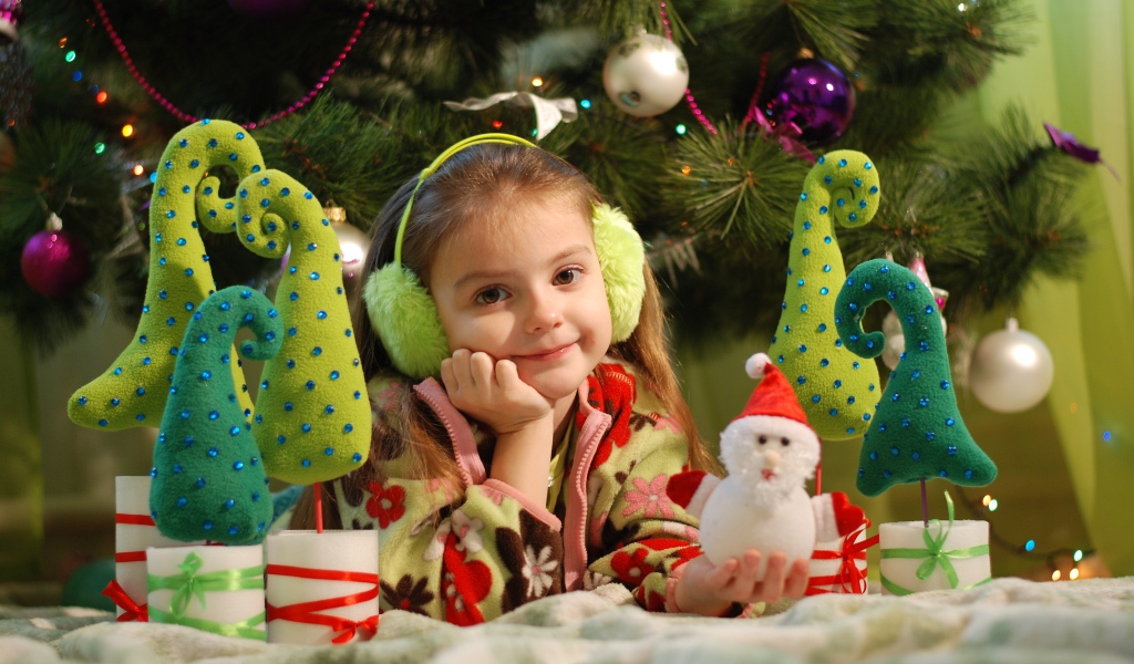Милая маленькая девочка с игрушками под елкой 
