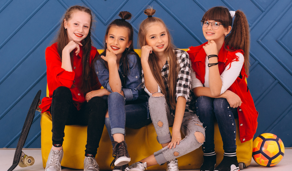 Четыре модных девочки сидят на диване 