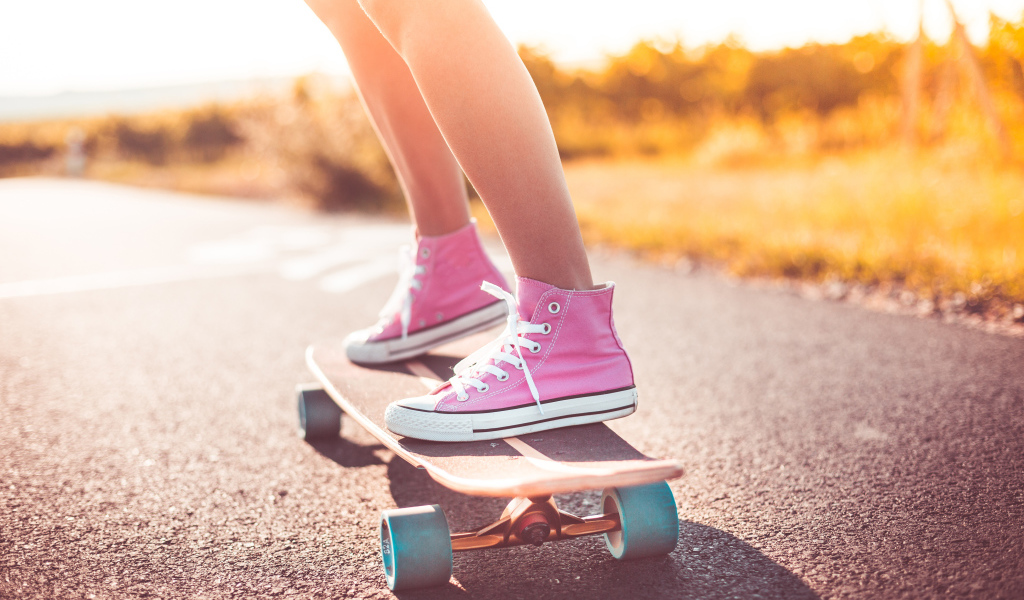 Девочка в розовых кедах едет на скейтборде