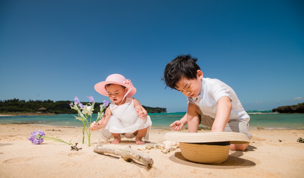 Маленькие дети азиаты играют на песке у моря 