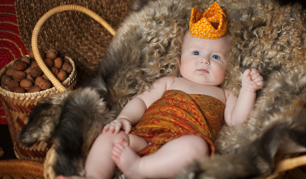 Маленький грудной ребенок в короне лежит в корзине 