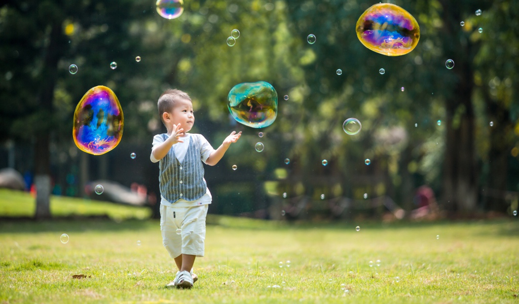 Маленький мальчик ловит мыльные пузыри