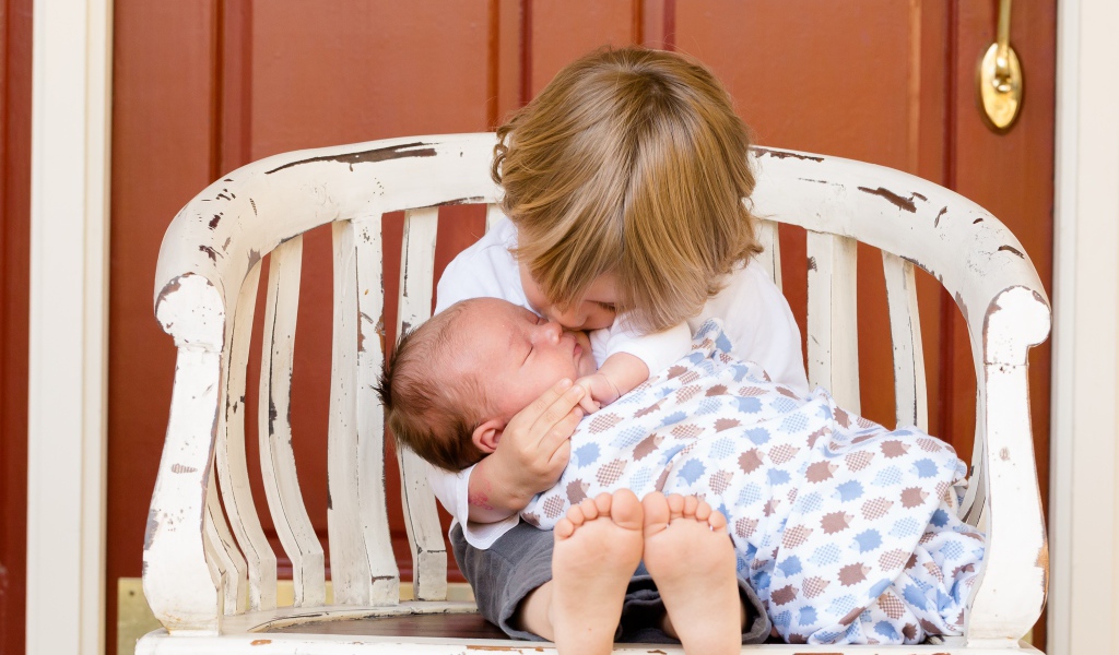 Маленькие мальчик держит брата на руках 