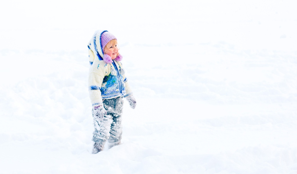 Маленькая веселая девочка гуляет по снегу