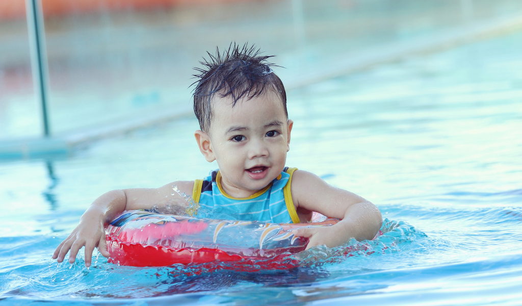 Маленький ребенок со спасательным кругом в бассейне 
