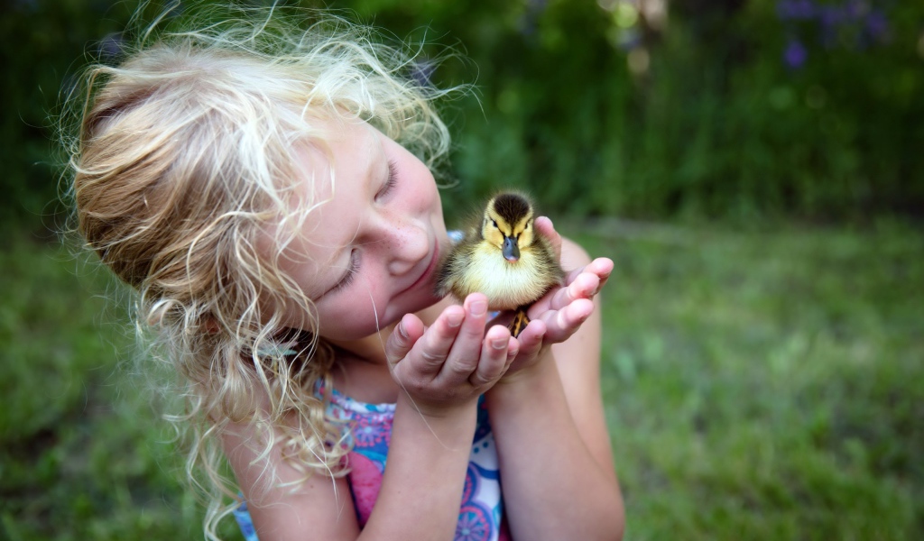 Маленькая милая девочка с утенком в руке