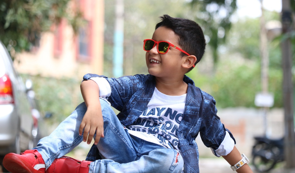 Маленький модный мальчик сидит на асфальте