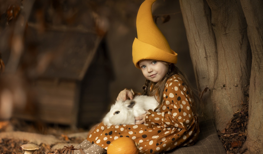 Маленькая смешная девочка в колпаке с кроликом