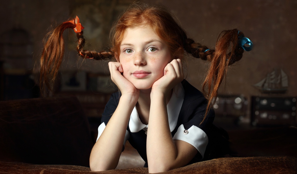 Маленькая смешная девочка с косами в школьной форме 