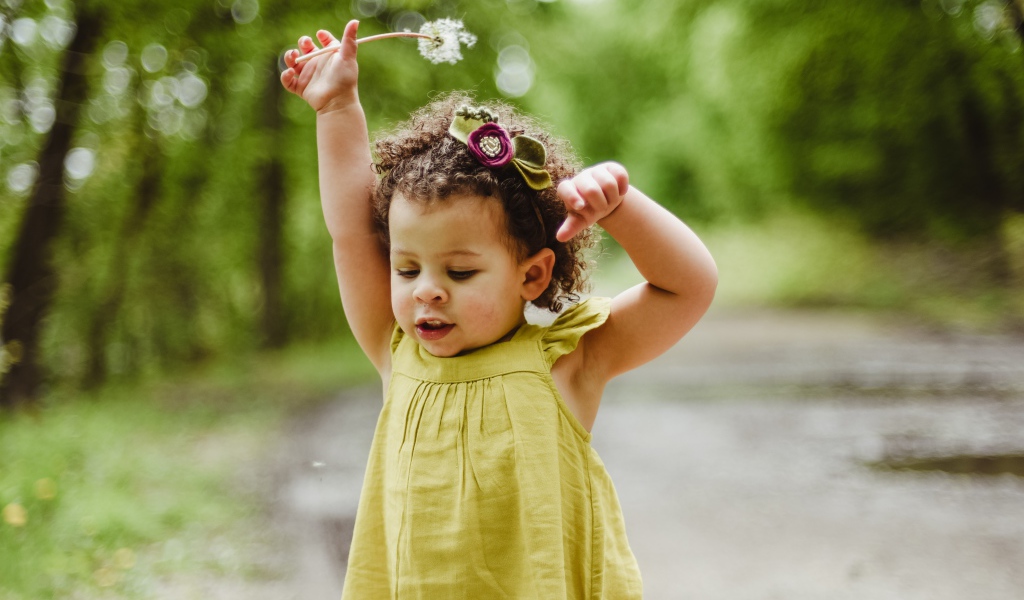 Little girl in a dress with a dandelion