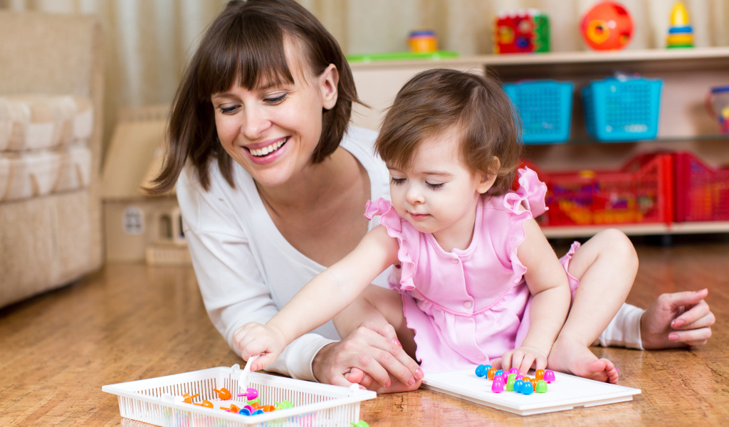 Маленькая девочка в розовом платье играет с мамой