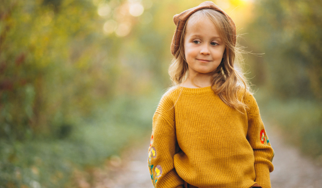 Маленькая девочка в свитере гуляет в лесу
