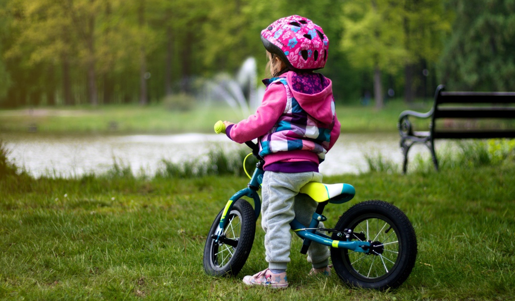Маленькая девочка на велосипеде в парке 