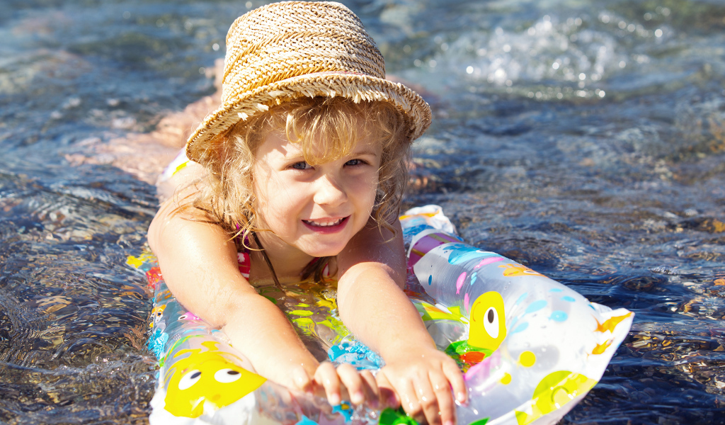 Маленькая девочка на надувном матрасе в воде