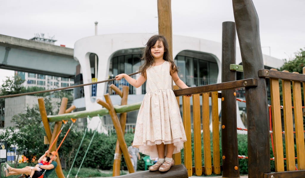 Маленькая девочка стоит на детской площадке 