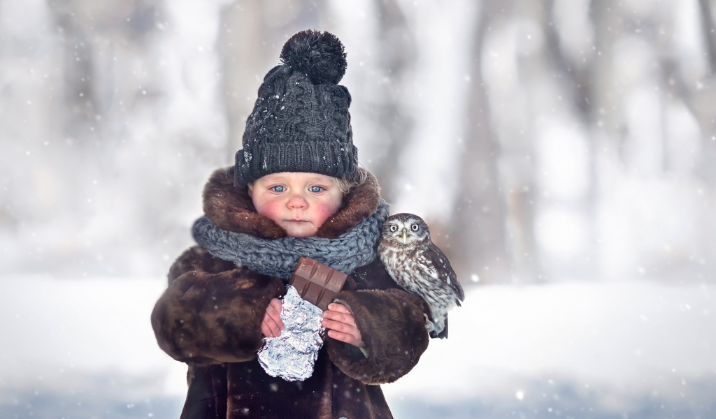 Маленькая девочка с шоколадкой в руках на улице зимой