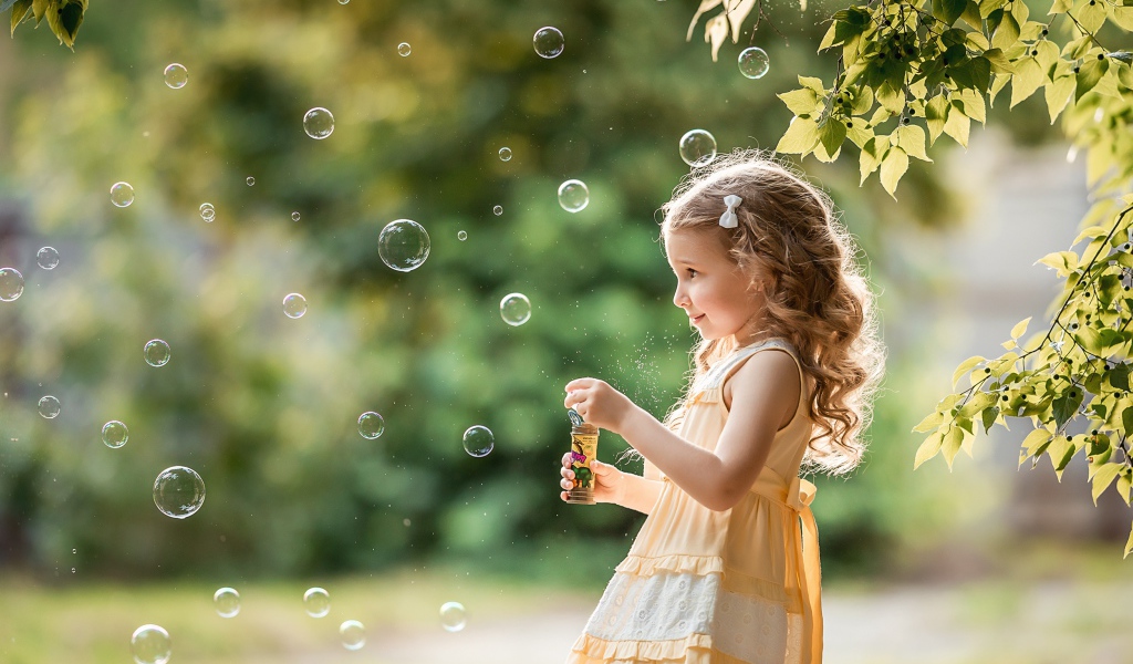 Маленькая девочка с мыльными пузырями в саду 