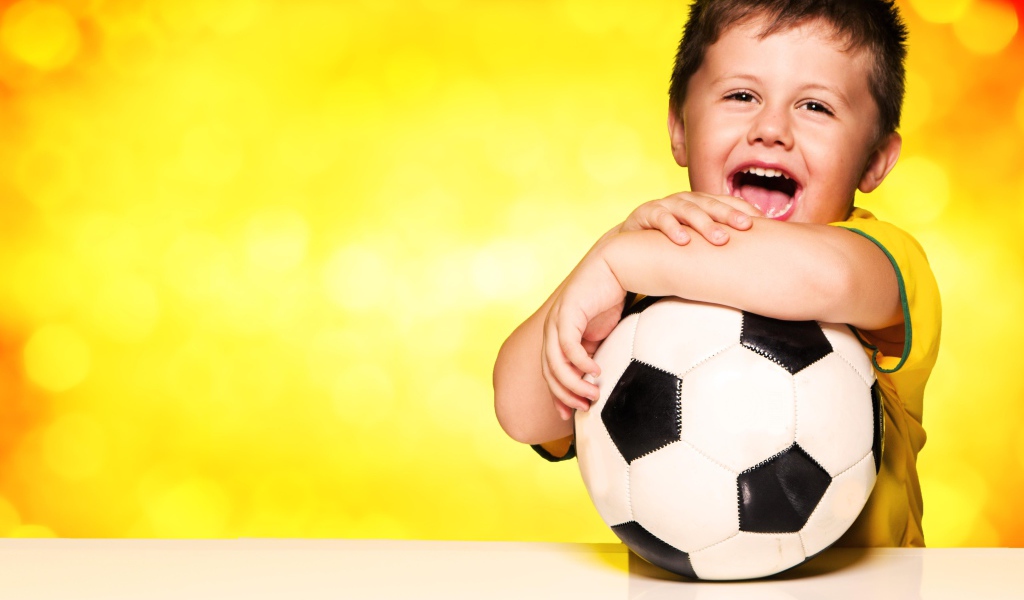 Маленький довольный мальчик с футбольным мячом